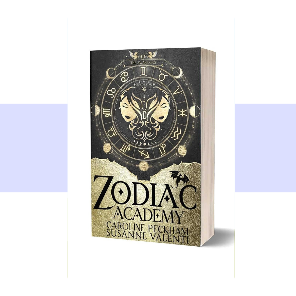 A dark fantasy cover for Zodiac Academy 1: The Awakening featuring a predominantly black background with an ornate circular celestial and zodiac-inspired emblem in blue and gold near the top. The design incorporates astrological symbols and intricate decorative details, creating a mysterious, magical academy aesthetic. The title "ZODIAC ACADEMY" appears prominently in large gold lettering, with "THE AWAKENING" beneath it in smaller gold text. Caroline Peckham and Susanne Valenti's names appear in gold.